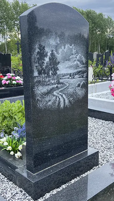 Гранитный памятник с гравировкой пейзажа с дорогой, деревьями и облаками